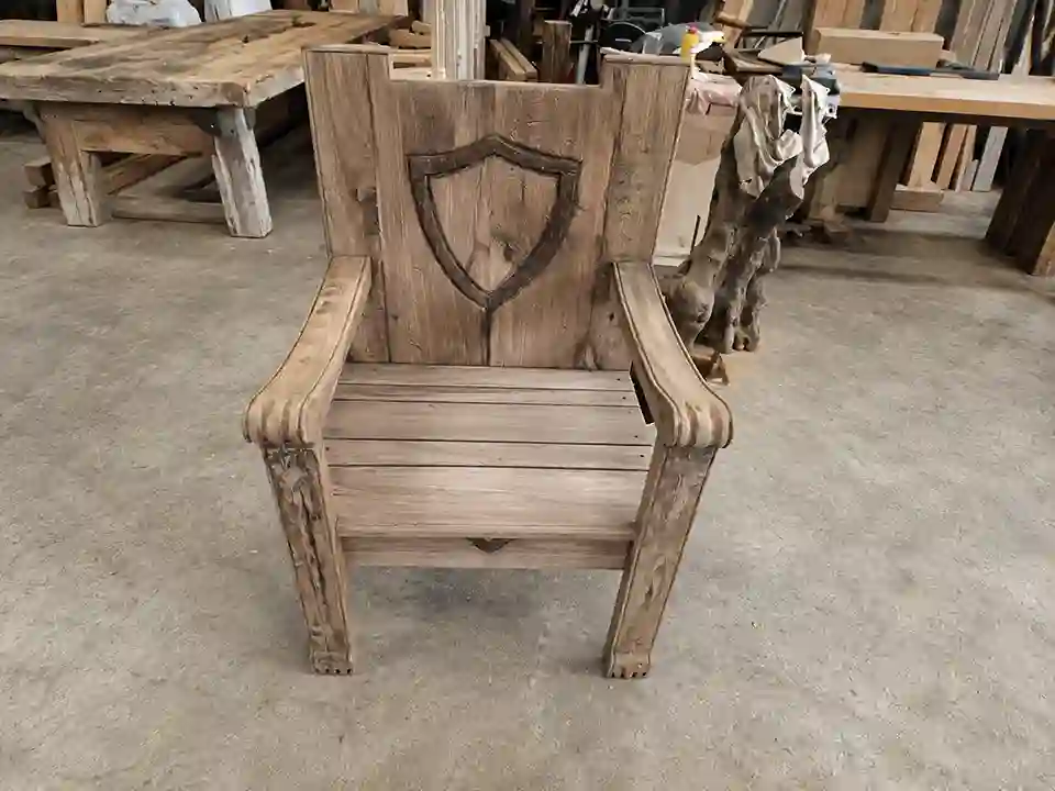 Custom hand-carved reclaimed wood armchair with shield motif for rustic hospitality interiors