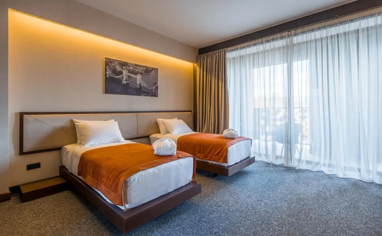 Twin beds with a shared upholstered headboard and wooden bed frames at Bridge Hotel, Tbilisi.